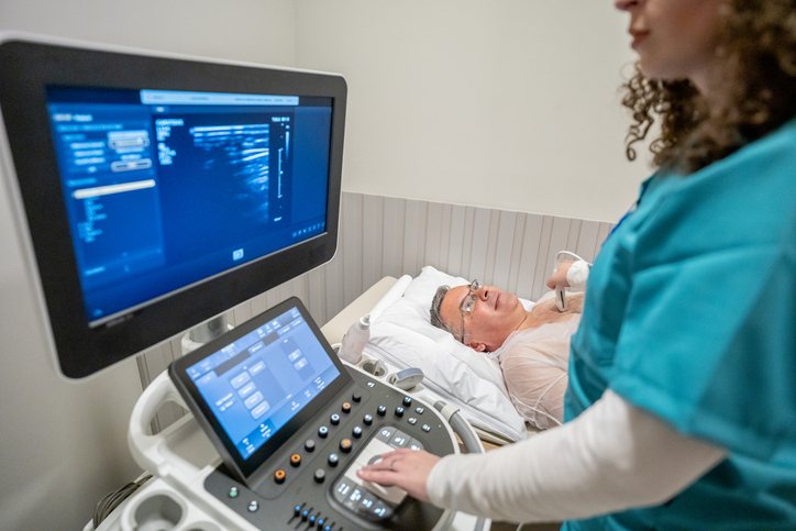 A sonographer at the ultrasound machine during a study with an older patient