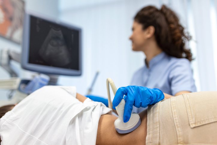 A sonographer watches the monitor during an abdominal ultrasound of the kidneys